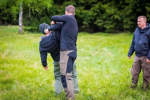 Zwei Personen üben eine Selbstverteidigungstechnik auf einer Wiese aus