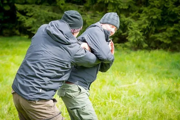 Zwei Personen üben eine Selbstverteidigungstechnik im Freien aus