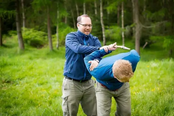 Zwei Personen üben eine Selbstverteidigungstechnik im Freien aus