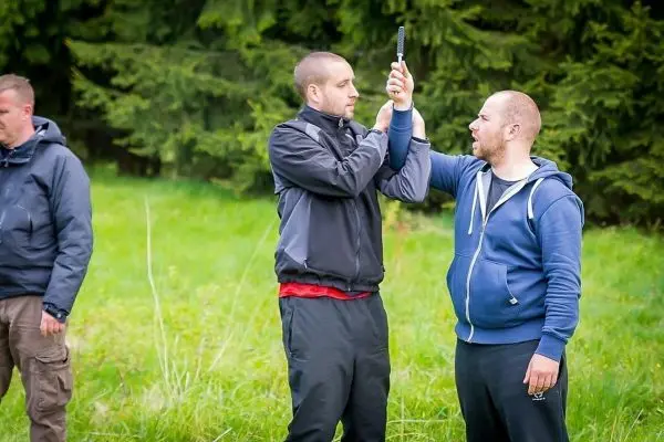 Zwei Personen üben eine Selbstverteidigungstechnik mit einem Stock im Freien