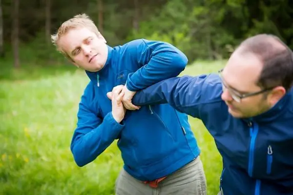 Zwei Personen üben eine Technik zur Selbstverteidigung im Freien aus