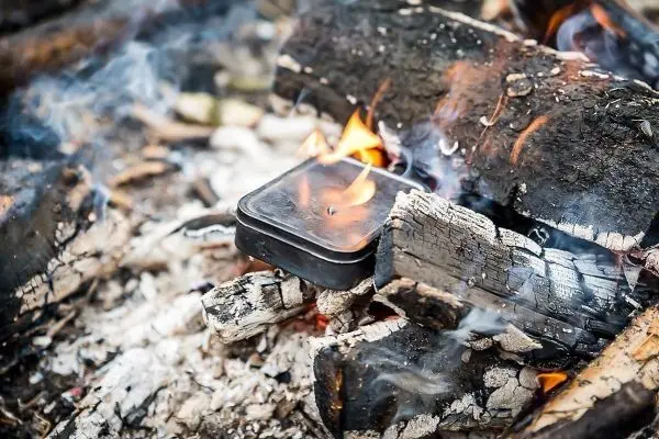 Ein Kochtopf steht auf brennenden Holzscheiten