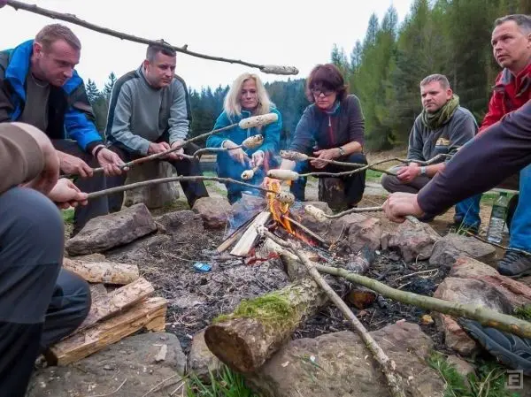 Grillspieße mit Teigstücken über einem offenen Feuer in einer Steinkreisfeuerstelle