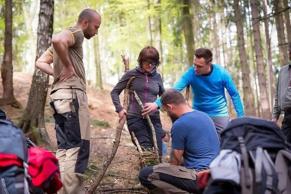 Gruppe arbeitet an einer selbstgebauten Konstruktion aus Ästen im Wald