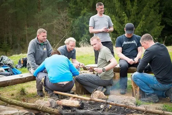Gruppe sitzt um ein kleines Bodenfeuer und bereitet Zunder vor