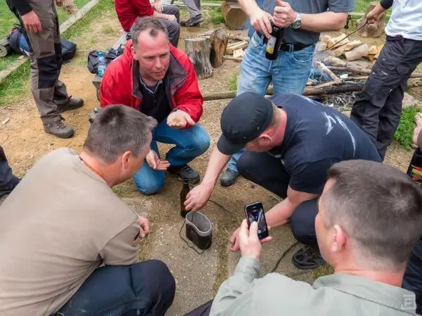 Gruppe um einen Kochtopf versammelt, während Zunder vorbereitet wird