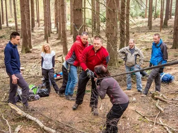 Gruppierung arbeitet gemeinsam an einer selbstgebauten Seilbrücke im Wald