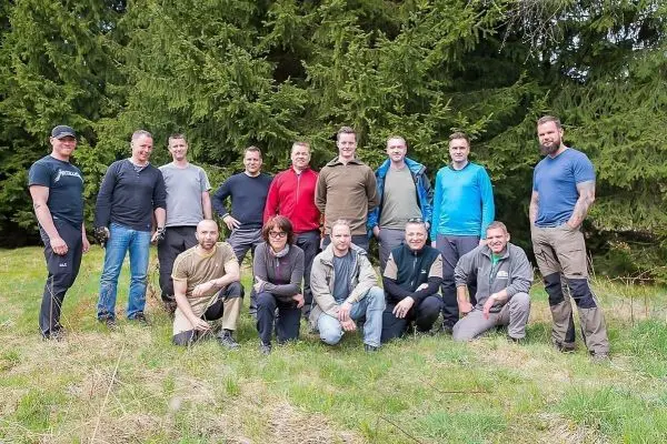 Gruppierung von Personen im Freien vor einer Baumreihe auf Wiese