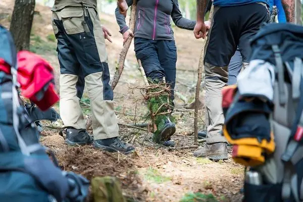 Gruppierung von Personen um eine selbstgebaute Konstruktion aus Ästen und Zweigen
