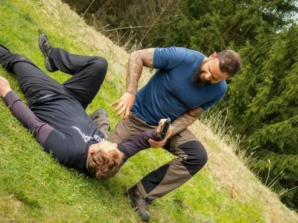 Kämpfer kontrolliert am Boden liegende Person mit festem Griff am Handgelenk