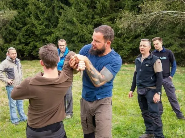 Kampftraining mit zwei Personen in einer Wiese, mehrere Zuschauer beobachten
