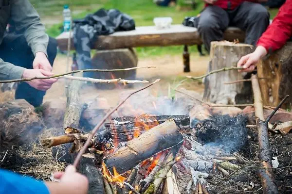 Kleines Bodenfeuer mit brennenden Holzstücken und Rauchentwicklung