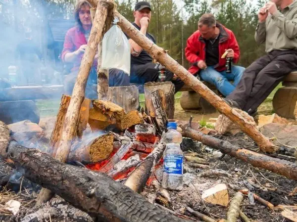 Kleines Bodenfeuer mit Holzscheiten und Wasserflasche in der Nähe