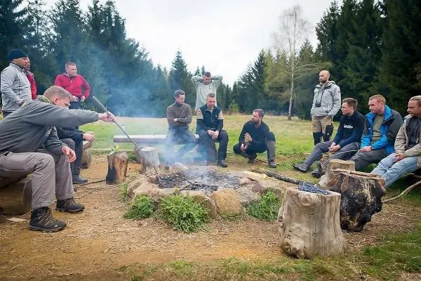 Kleines Bodenfeuer mit Rauch und mehreren Personen um das Feuer herum