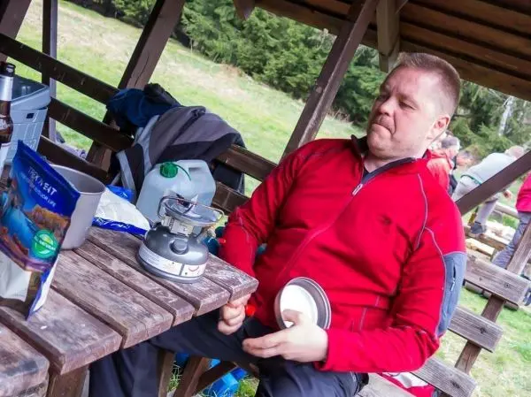 Kocher steht auf dem Tisch, Mann bereitet Essen in einer Schüssel vor