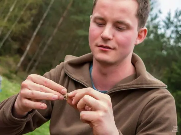 Mann hält ein kleines Objekt mit beiden Händen und betrachtet es aufmerksam