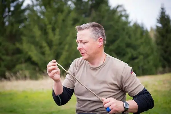Mann hält einen Stock in der Hand und betrachtet ihn aufmerksam