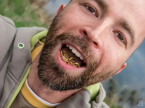 Mann mit Insekten im Mund lächelt in die Kamera