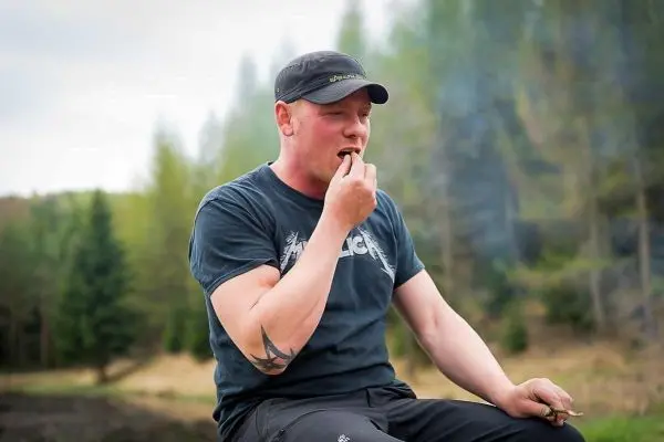 Mann sitzt im Freien und isst etwas