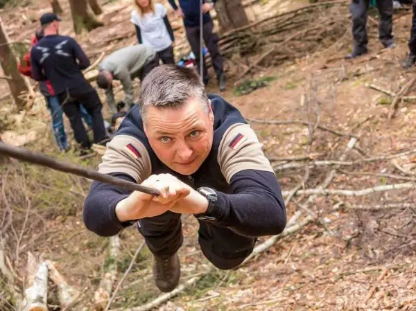 Mann überquert eine selbstgebaute Seilbrücke im Wald