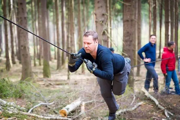 Mann überquert eine selbstgebaute Seilbrücke im Wald
