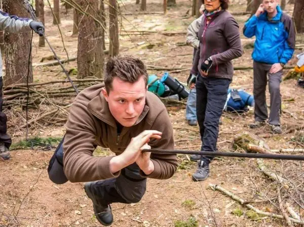 Mann überquert selbstgebaute Seilbrücke in einem Waldgebiet
