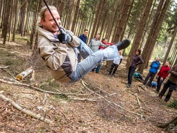 Mann überquert selbstgebaute Seilbrücke zwischen Bäumen im Wald
