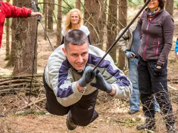 Mann überquert selbstgebaute Seilbrücke zwischen Bäumen im Wald