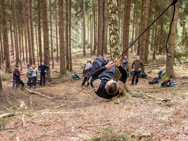 Mann überquert selbstgebaute Seilbrücke zwischen Bäumen im Wald