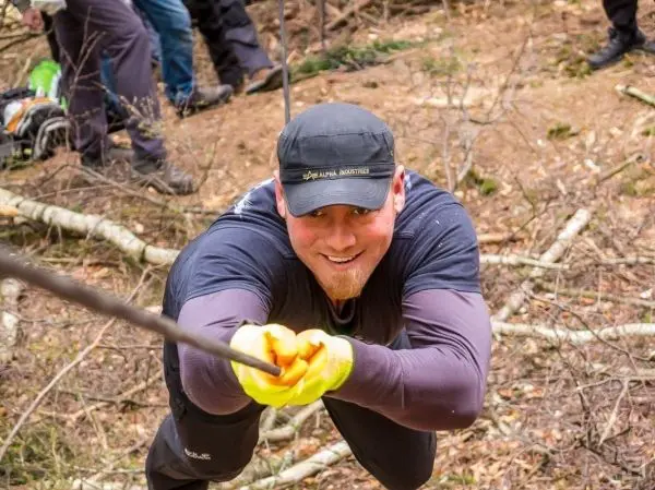 Mann zieht an einem Seil in einem bewaldeten Gebiet