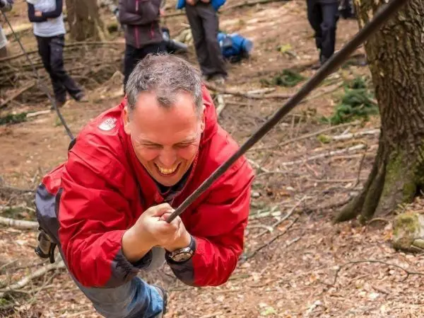 Mann zieht an einem Seil in einem Waldgebiet