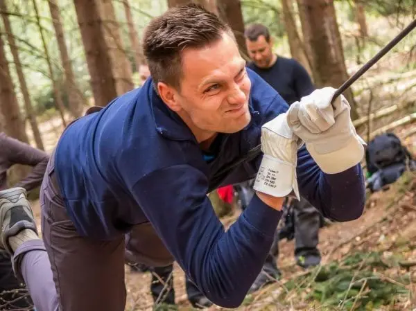 Mann zieht an einem Seil in einem Waldgebiet