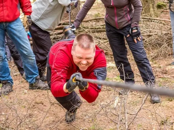 Mann zieht an einem Seil während einer Gruppenaktivität im Wald