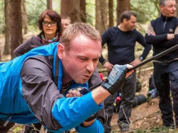 Mann zieht an einem Seil während einer Gruppenübung im Wald
