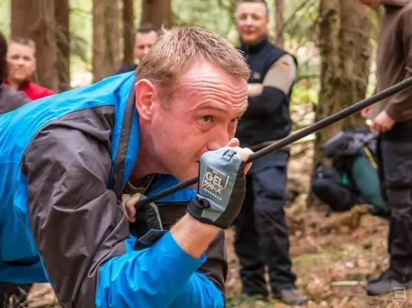 Mann zieht an einem Seil während einer Seilquerung im Wald