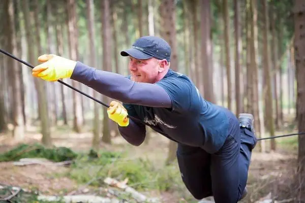 Mann zieht sich an einem Seil in einem Wald nach vorne