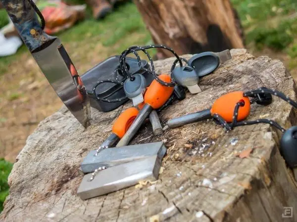 Messer, Feuerstahl und Werkzeuge liegen auf einem Baumstumpf