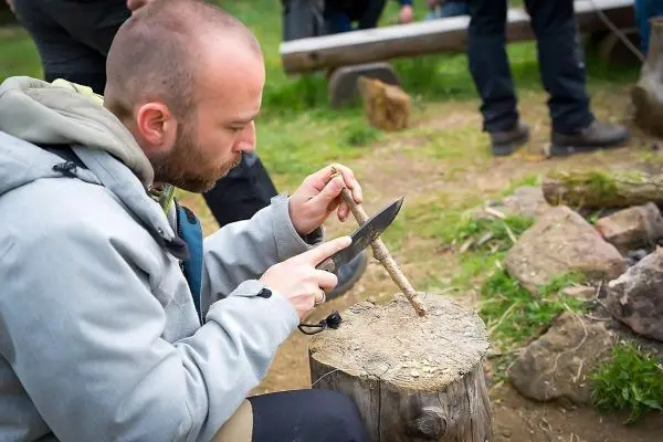 Messer schneidet Holzstück auf einem Baumstumpf während einer Outdoor-Aktivität