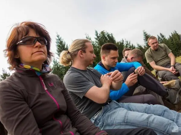 Person sitzt mit Gruppe im Freien und schaut nachdenklich