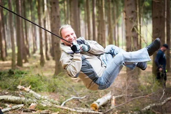 Person überquert eine selbstgebaute Seilbrücke im Wald