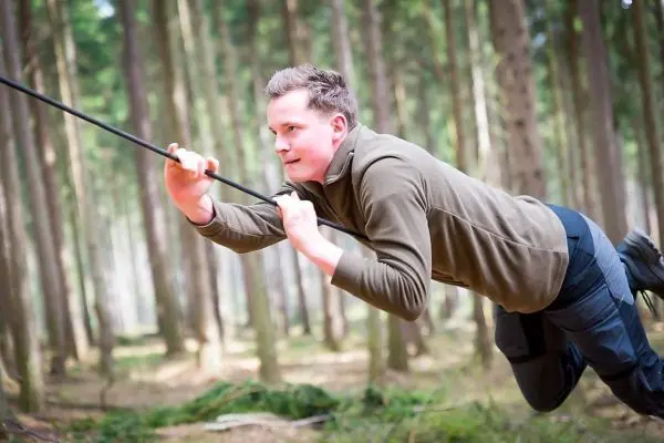 Person zieht sich an einem Seil durch den Wald