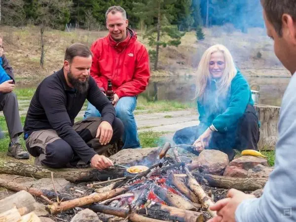 Personen sitzen um ein Feuer und grillen Lebensmittel