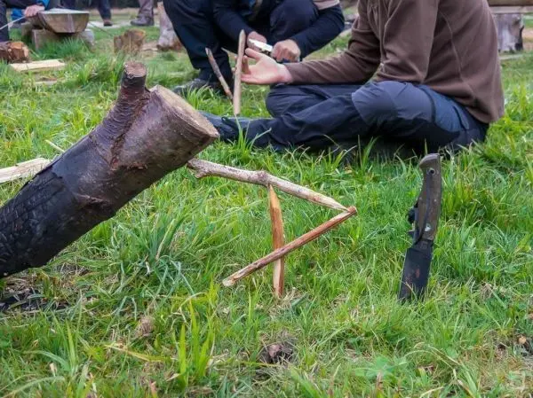 Schlagfalle (Figure-Four) mit Holzstücken und Messer auf dem Boden