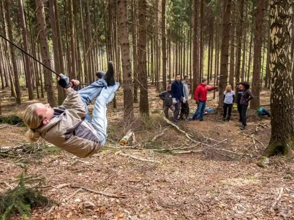 Selbstgebaute Seilquerung wird von einer Person überquert, während andere zuschauen