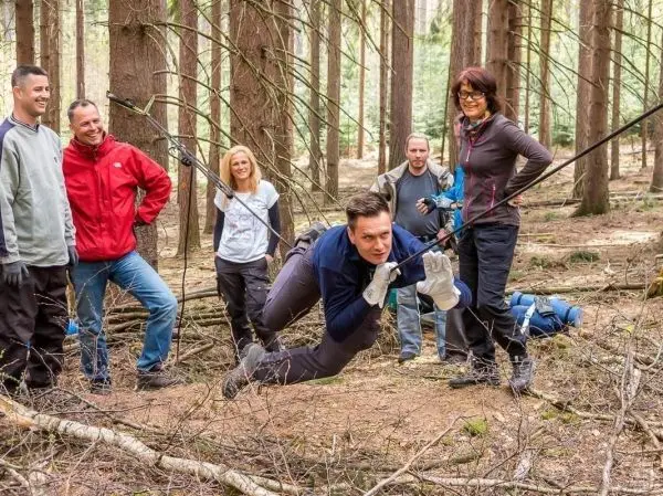 Selbstgebaute Seilquerung wird von einer Person überquert, während andere zuschauen