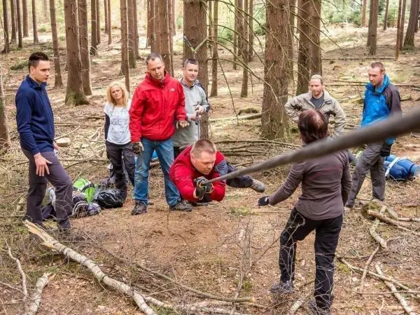 Teilnehmer überqueren eine selbstgebaute Seilbrücke im Wald