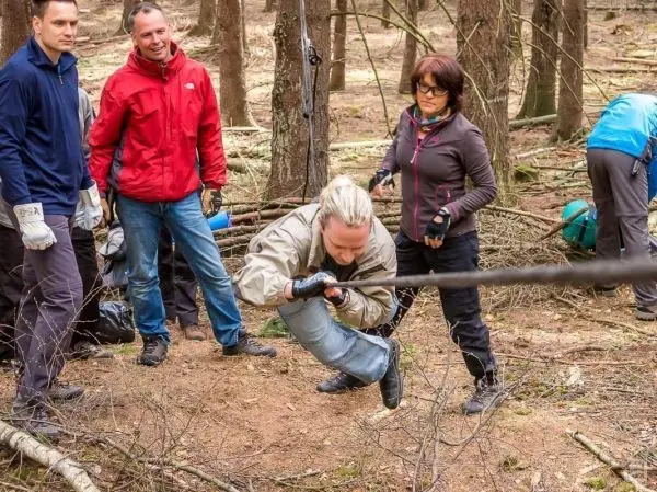Teilnehmer überquert eine selbstgebaute Seilbrücke im Wald