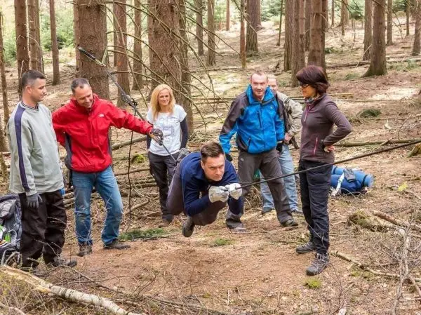 Teilnehmer überquert eine selbstgebaute Seilbrücke im Wald