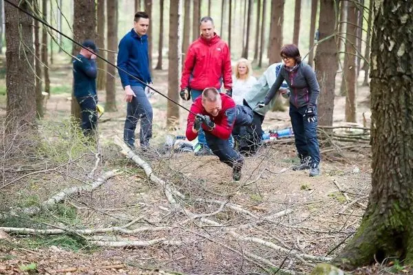 Teilnehmer überquert eine selbstgebaute Seilbrücke zwischen Bäumen