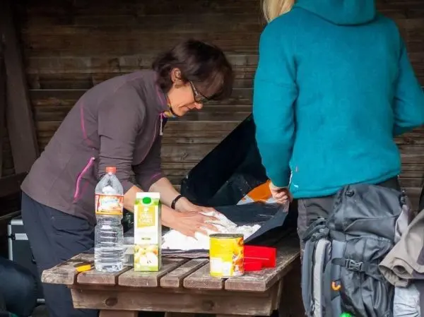 Zwei Personen bereiten Lebensmittel auf einem Tisch in einer Hütte vor